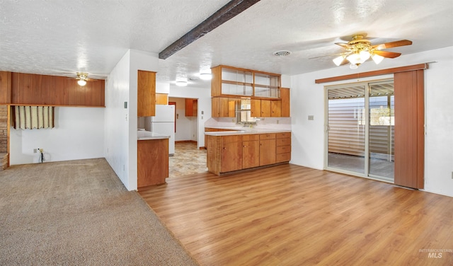kitchen featuring brown cabinets, a ceiling fan, light countertops, a textured ceiling, and freestanding refrigerator