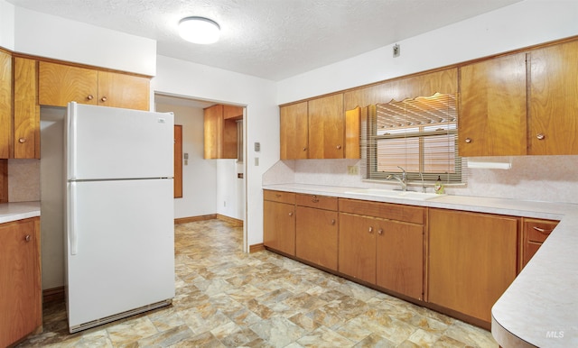 kitchen featuring a sink, freestanding refrigerator, and light countertops