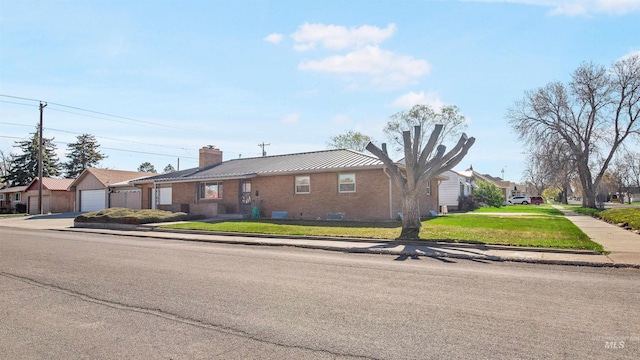 view of front of property featuring a front lawn, a residential view, metal roof, a chimney, and brick siding