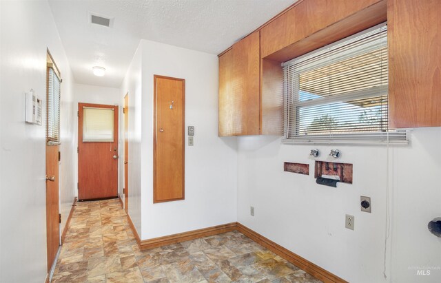 washroom featuring hookup for an electric dryer, visible vents, stone finish floor, and baseboards