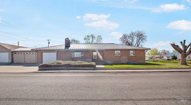 view of front facade with a chimney, a standing seam roof, brick siding, metal roof, and concrete driveway