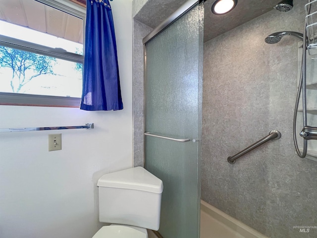 bathroom with a shower with shower door and toilet