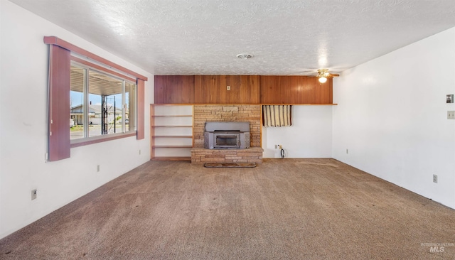 unfurnished living room featuring a fireplace, a textured ceiling, ceiling fan, and carpet floors
