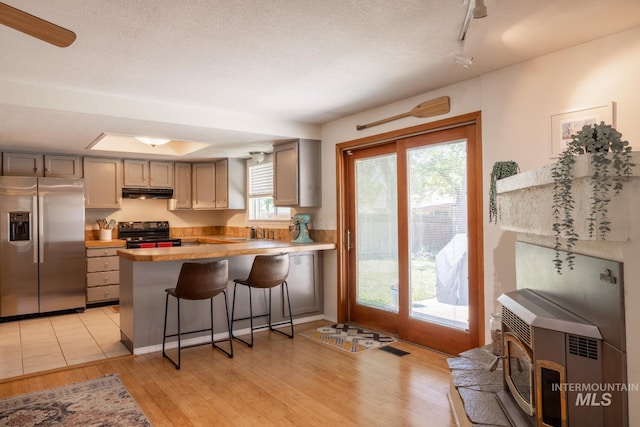 3929 N Shamrock Ave, Boise, ID 83713 - kitchen with stainless steel refrigerator with ice dispenser, black range with electric cooktop, under cabinet range hood, a peninsula, and light wood-style floors