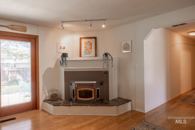 3929 N Shamrock Ave, Boise, ID 83713 - living area featuring rail lighting, wood finished floors, a wood stove, and arched walkways