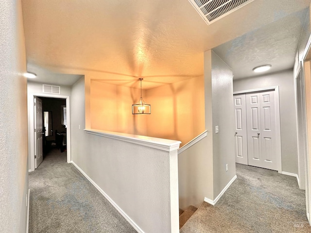 corridor with carpet and a textured ceiling