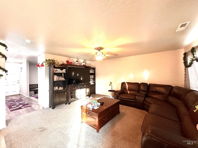 carpeted living room featuring ceiling fan and a textured ceiling