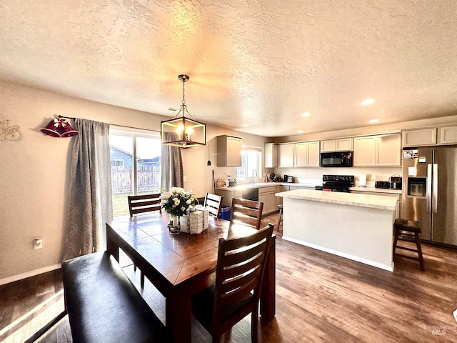 dining area with a textured ceiling, dark wood-type flooring, a wealth of natural light, and sink