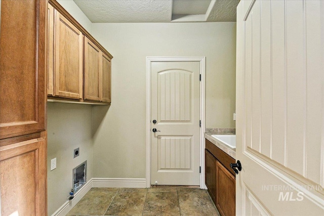 clothes washing area featuring cabinets, a textured ceiling, and hookup for an electric dryer