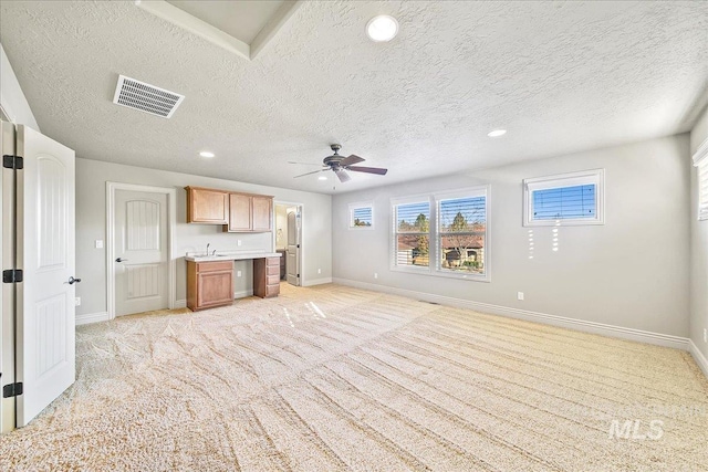 unfurnished living room featuring a textured ceiling, ceiling fan, and light carpet