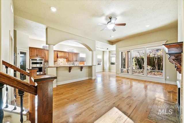 living room with ceiling fan, light hardwood / wood-style floors, sink, and a textured ceiling