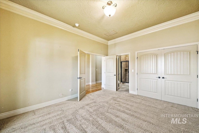 unfurnished bedroom with crown molding, a closet, light carpet, and a textured ceiling