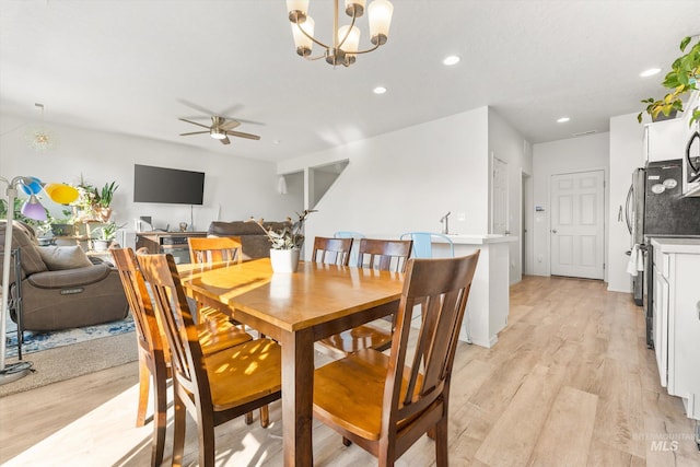 dining area with light hardwood / wood-style flooring and ceiling fan with notable chandelier