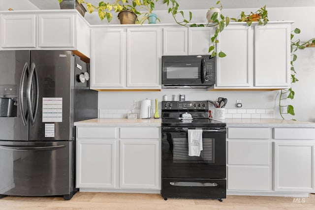 kitchen with black appliances, white cabinets, and light wood-type flooring