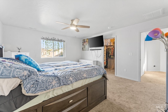 bedroom featuring a closet, ceiling fan, light carpet, and a walk in closet