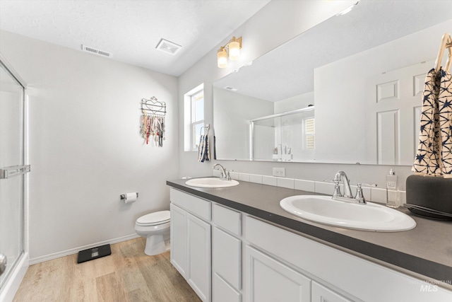 bathroom featuring vanity, wood-type flooring, toilet, and an enclosed shower