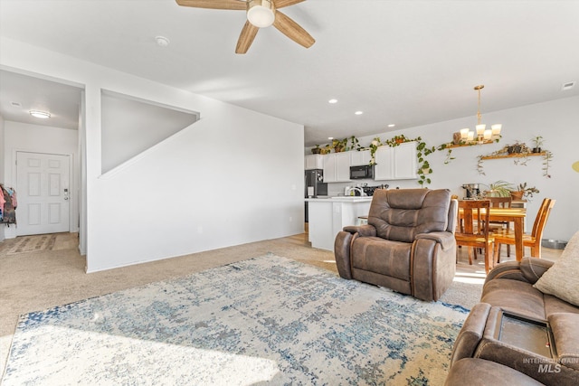 carpeted living room with ceiling fan with notable chandelier