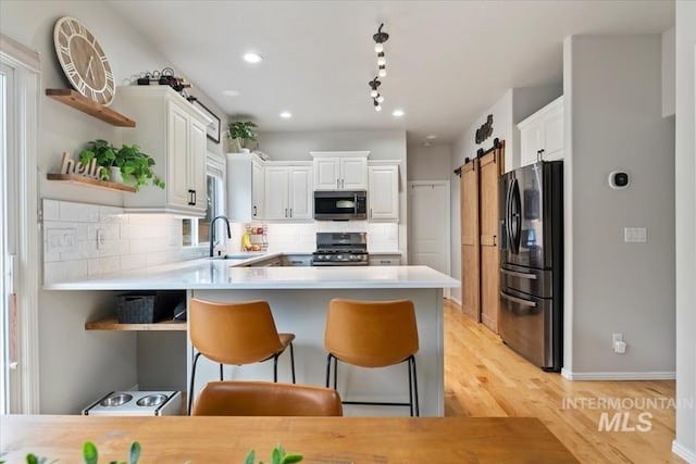 10450 W Antietam St, Boise, ID 83709 - kitchen with open shelves, a peninsula, white cabinets, a sink, and appliances with stainless steel finishes