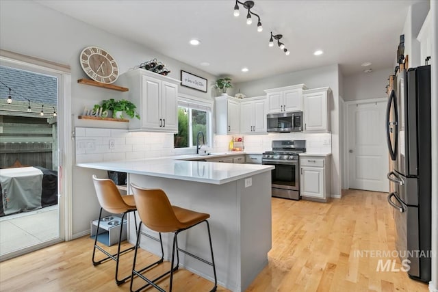 10450 W Antietam St, Boise, ID 83709 - kitchen featuring white cabinets, a breakfast bar area, stainless steel appliances, a peninsula, and decorative backsplash