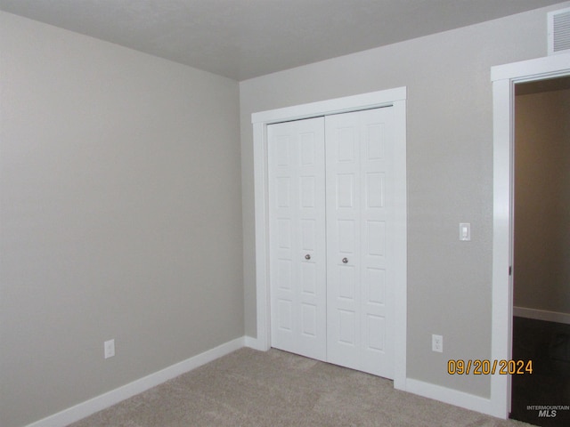 unfurnished bedroom featuring a closet and light carpet