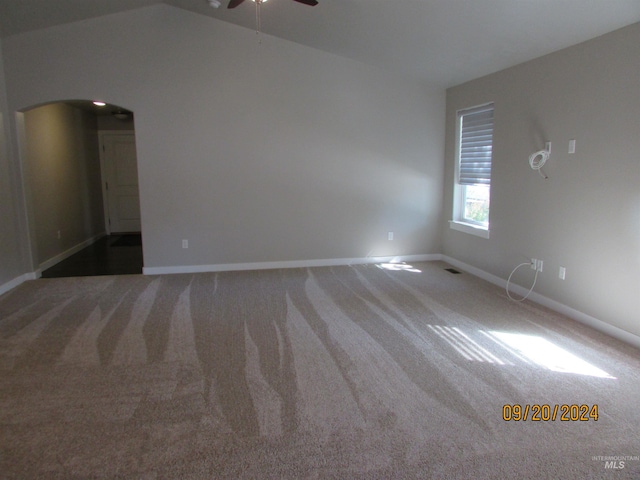 spare room featuring ceiling fan, vaulted ceiling, and dark colored carpet