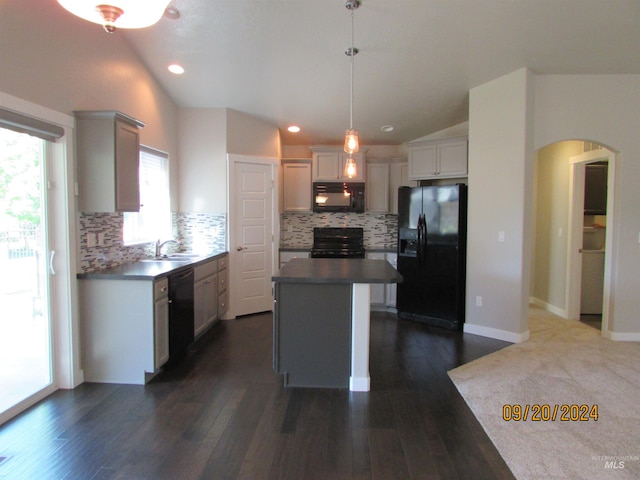 kitchen with black appliances, a center island, decorative light fixtures, vaulted ceiling, and dark hardwood / wood-style floors