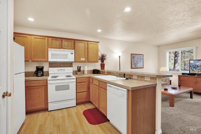 kitchen featuring white appliances, light countertops, a sink, and a peninsula