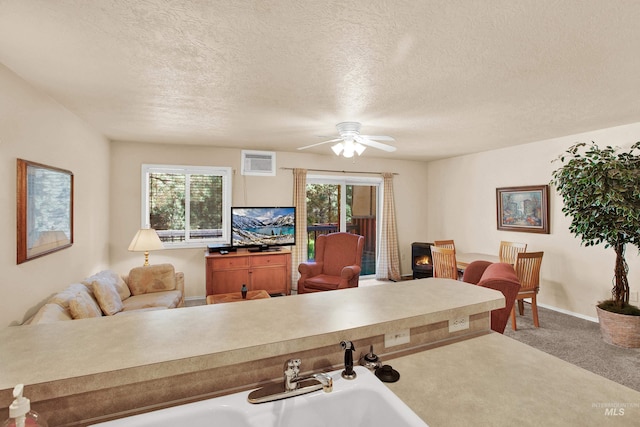 living room with baseboards, ceiling fan, carpet flooring, and a textured ceiling