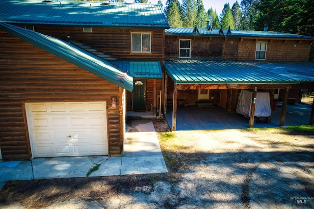 view of front of property featuring faux log siding, driveway, and metal roof