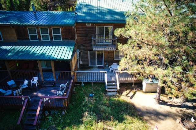 rear view of property featuring metal roof, a jacuzzi, stairs, and a deck