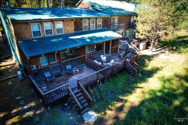 rear view of house with metal roof, stairway, and a yard