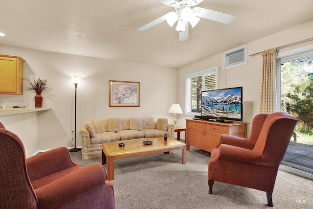 living room featuring light carpet, a wall mounted AC, ceiling fan, and a textured ceiling