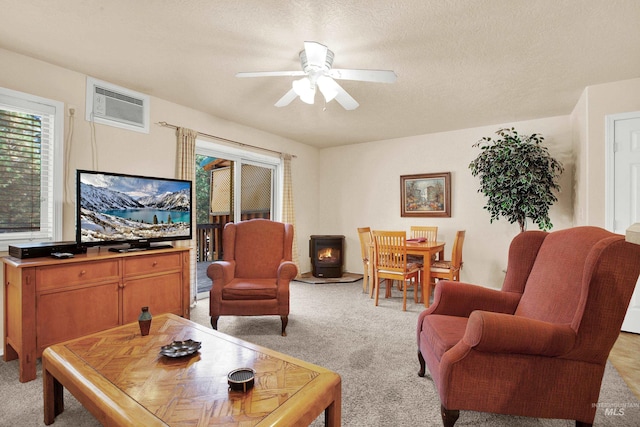 living room featuring a wall mounted AC, a textured ceiling, light colored carpet, and ceiling fan