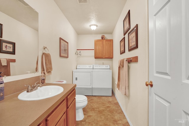 bathroom featuring independent washer and dryer, vanity, toilet, and visible vents