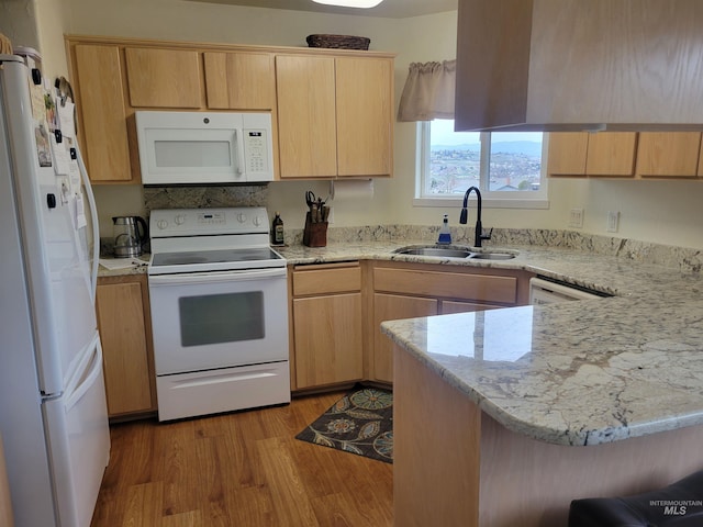 kitchen featuring light brown cabinetry, a sink, wood finished floors, white appliances, and a peninsula