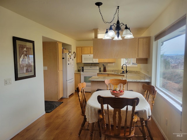 dining space with a notable chandelier, wood finished floors, and baseboards