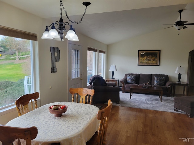 dining area featuring ceiling fan with notable chandelier, dark wood-style floors, and vaulted ceiling