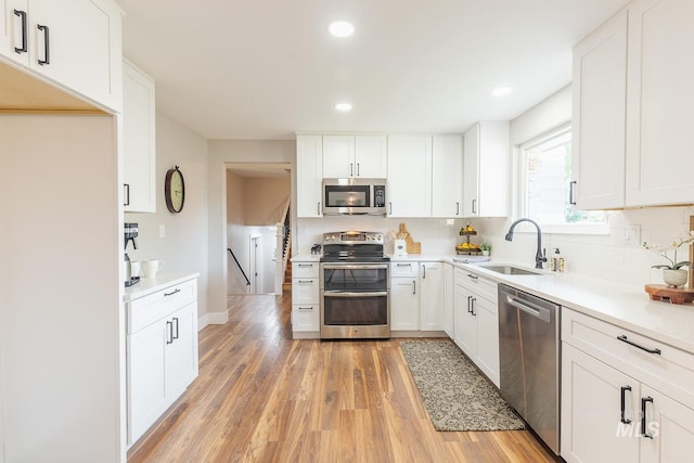 5696 N Kriscliffe, Boise, ID 83704 - kitchen with appliances with stainless steel finishes, tasteful backsplash, a sink, light wood-style floors, and white cabinets