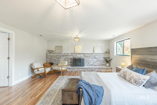 5696 N Kriscliffe, Boise, ID 83704 - bedroom featuring a stone fireplace, wood finished floors, and baseboards