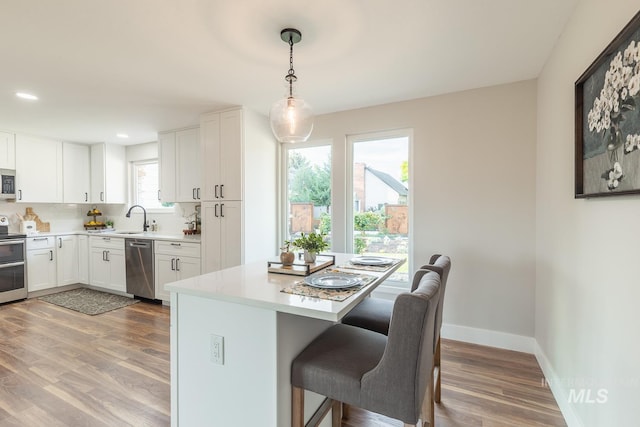 5696 N Kriscliffe, Boise, ID 83704 - kitchen with appliances with stainless steel finishes, a breakfast bar area, a sink, wood finished floors, and light countertops