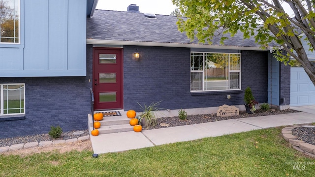 entrance to property with a garage and a lawn