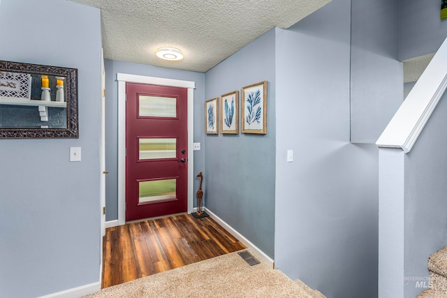 doorway with dark hardwood / wood-style floors and a textured ceiling