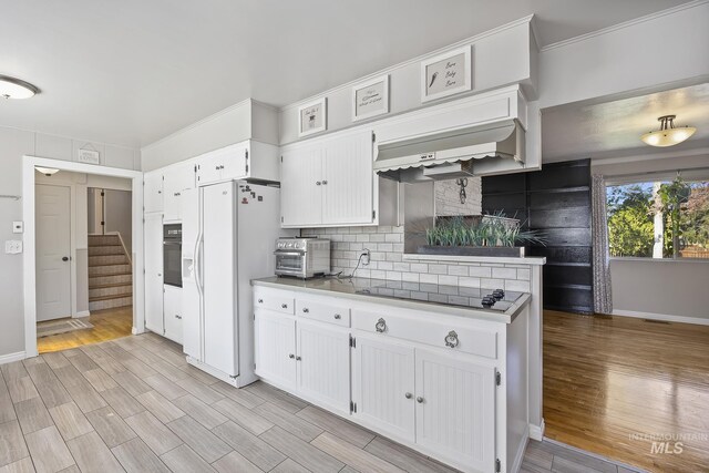 827 Alturas Dr N, Twin Falls, ID 83301 - kitchen with black appliances, a toaster, light wood finished floors, backsplash, and white cabinetry