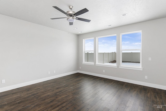 unfurnished room with dark wood finished floors, a textured ceiling, and baseboards