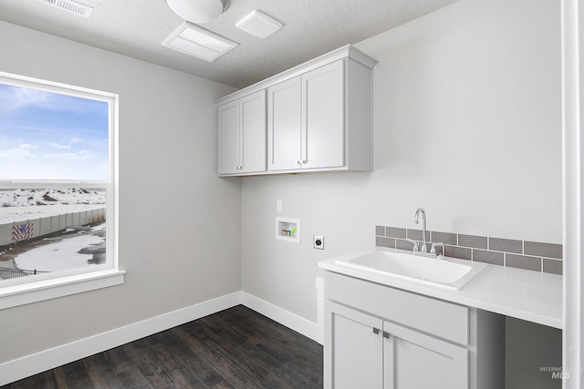 washroom with hookup for an electric dryer, dark wood-type flooring, washer hookup, a sink, and cabinet space