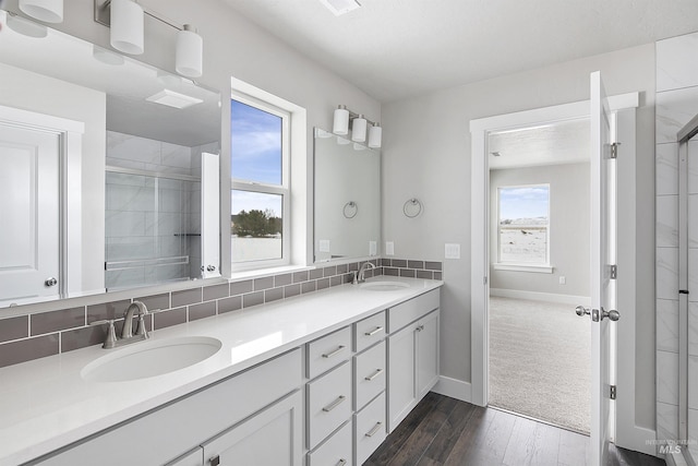 full bathroom featuring double vanity, a stall shower, backsplash, and a sink