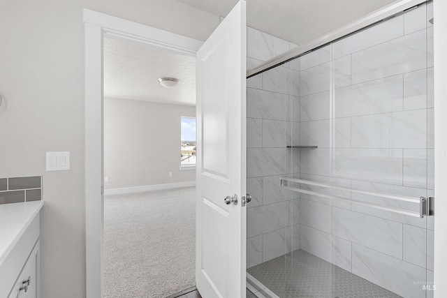 bathroom featuring a stall shower, a textured ceiling, baseboards, and vanity