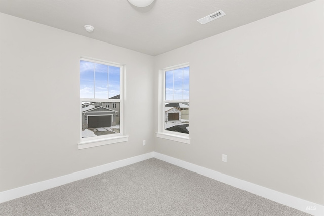 empty room featuring carpet floors, visible vents, and baseboards