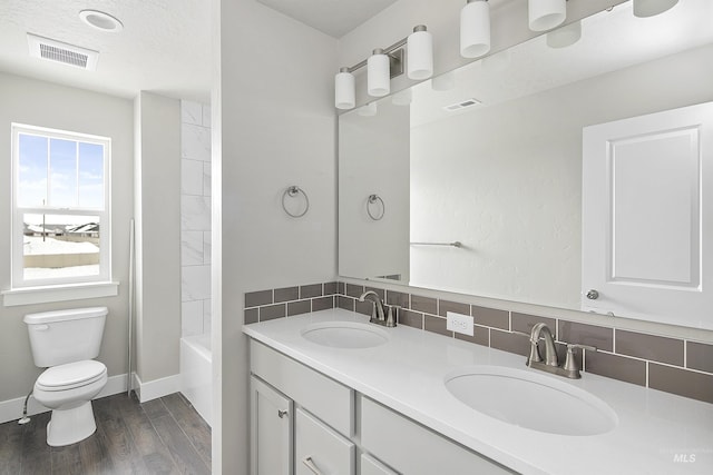 bathroom featuring tasteful backsplash, visible vents, and a sink