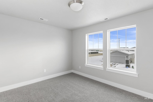 spare room featuring baseboards, visible vents, and carpet flooring